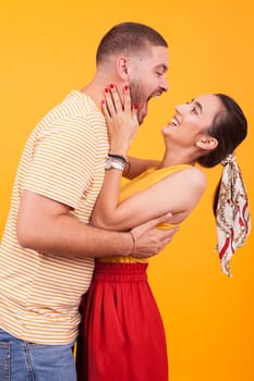 Cheerful young couple in studio over yellow background. Happy and romantic young couple