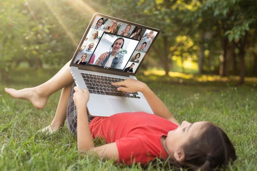 Home schooling. A girl is sitting at a table with a laptop during an online video chat of a school lesson with a teacher and class. Concept of distance education. Self-isolation in quarantine