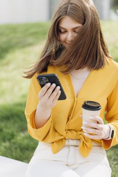 Young businesswoman scrolling smartphone near office space. Attractive business woman using smart phone on workplace. Portrait of pretty girl reading funny message on mobile phone outside office.