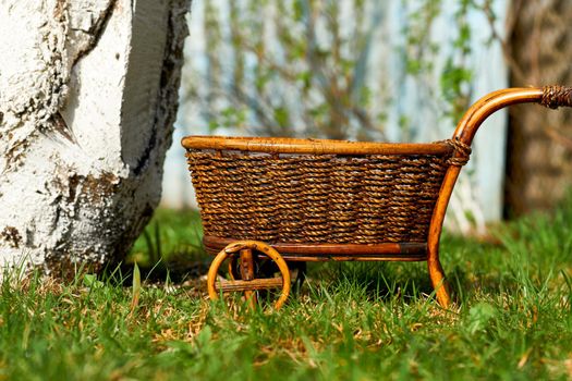 a strong open vehicle with two or four wheels, typically used for carrying loads and pulled by a horse. Wooden wicker brown cart on pink steps.