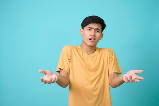 Portrait of confused young man shrugging his shoulders posing.