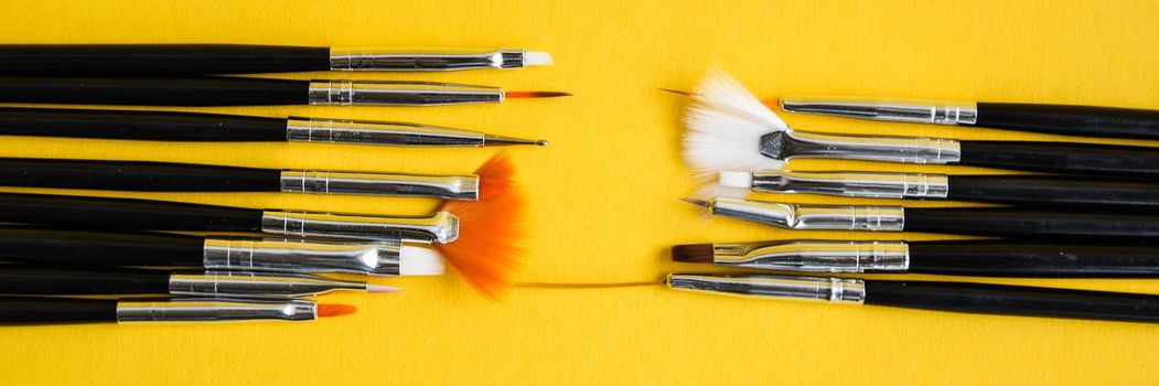 black brushes for nail design on yellow background, Manicure tools brushes for drawing on nails, copy space, top view, Nail artist work place