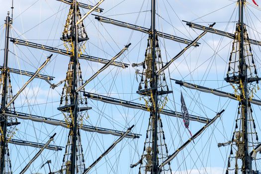 Masts of old ship against blue sky. Close-up