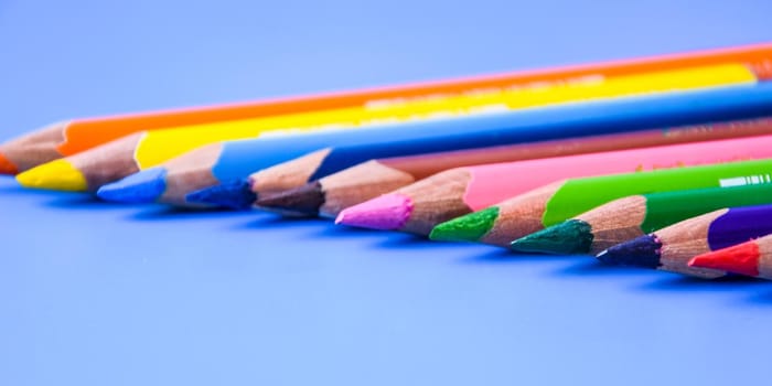 Crayons Colored pencils background. Color pencils on blue background. Close up. Copy space, top view of colorful various pencils placed in row