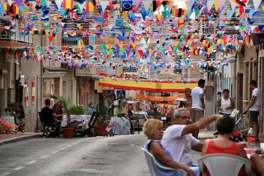 Santa Pola, Alicante, Spain- September 3, 2019: Street of Santa Pola decked out with colored flags and garlands for its festivities in September.