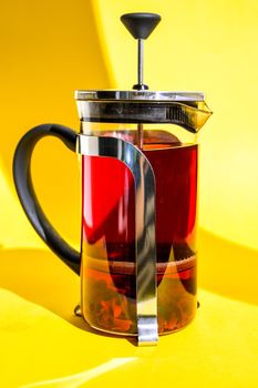 Fresh brewed spicy fruit tea with herbs, rose flowers, hot healthy drink on yellow background with copy space for text, Hibiscus tea, flower and dry blossom, glass teapot with hot tea