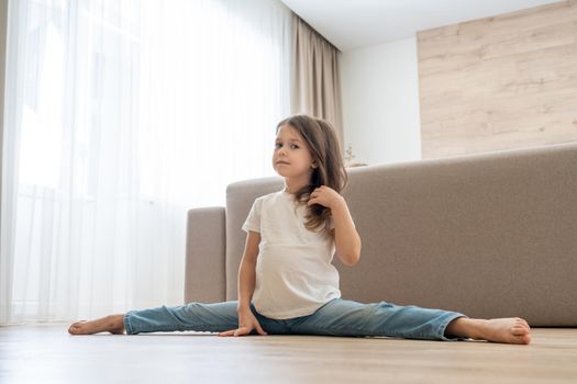 Little girl siting on a split in living room at home