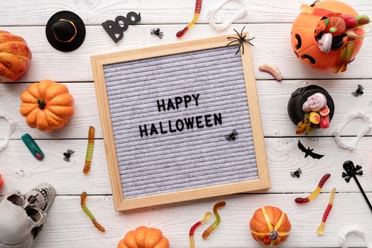Halloween concept. Happy Halloween words on gray letter board with candy flat lay on wooden background