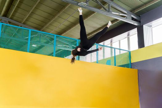 Young woman amateur acrobatic athlete jumping and exercising on a trampoline indoors