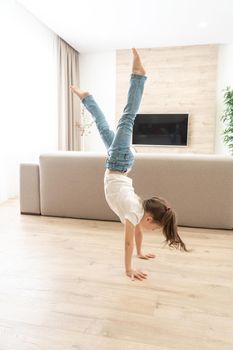 Little girl walking upside down on her arms at home