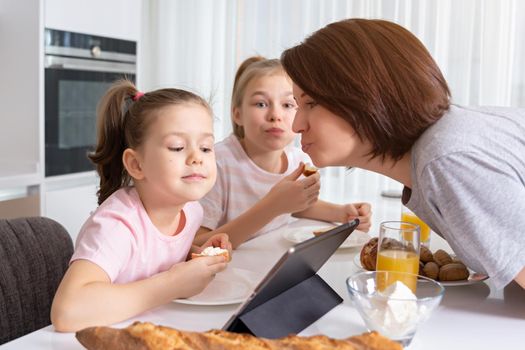 Mother trying to kiss daughter while having breakfast together