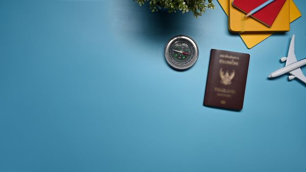 Top view, passport, airplane and round compass on blue background. Preparation for Traveling concept.