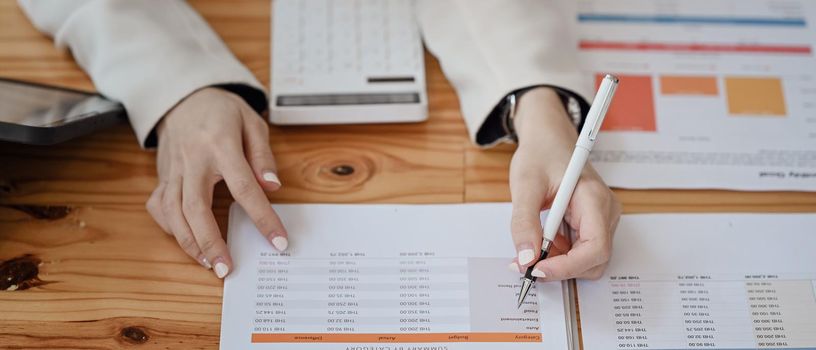 Cropped image of businesswoman analyzing financial document on wooden table.