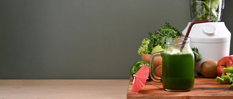 Healthy green vegetable smoothie and ingredients on wooden table. Vegetarian food concept.