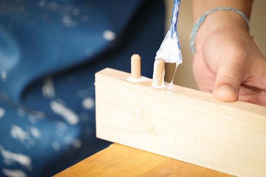 Woodworking operators are using glue to put together the wood parts to assemble and build a wooden table for their customers