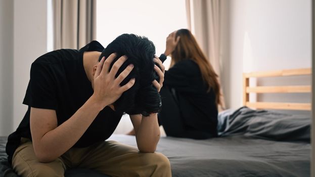 Young asian couple with relationship problem sitting on bed with their backs turned to each other. Family problems concept.