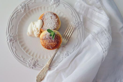 Cottage cheese pancakes, syrniki, ricotta fritters on white ceramic plate. Healthy and delicious morning breakfast. Copy space. White background. Top view, space for text, food background.