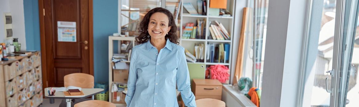 young beautiful smiling professional african american teacher portrait in school classroom.