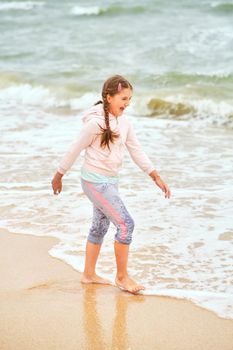 Happy child playing in the sea. Kid girl having fun at the beach. Summer vacation and active lifestyle concept