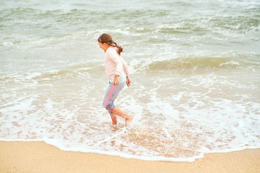 Happy child playing in the sea. Kid girl having fun at the beach. Summer vacation and active lifestyle concept