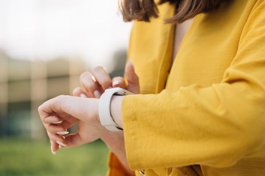 Caucasian woman using smartwatch digital device in the city. Smart watch. Scrolling display on smartwatch. Checking incoming notification on smart watch. Touch Screen Wearable Technology Smart Band.