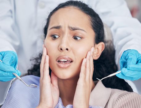 Shot of a young woman looking afraid at her dentists office.