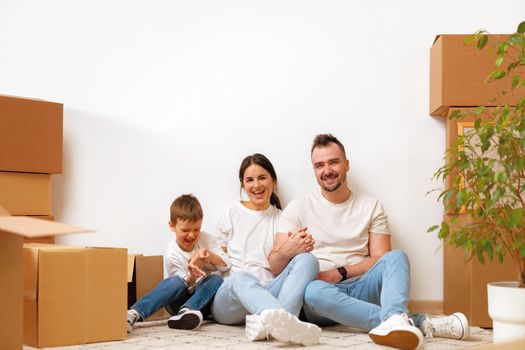 Young parents and son having fun during moving day to new house, portrait