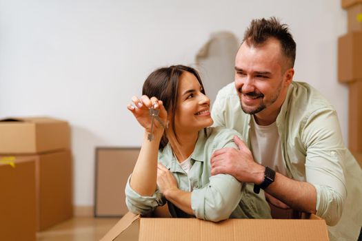 Young happy couple in room with lots of moving boxes at new home