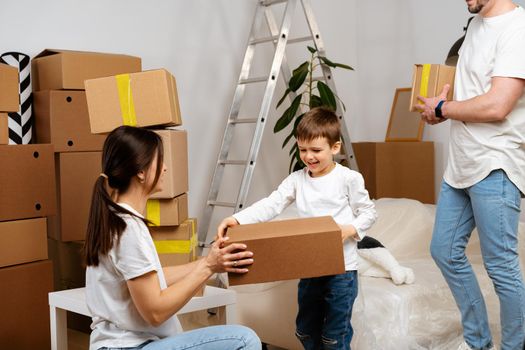 Parents and son packing boxes and moving into a new home having fun