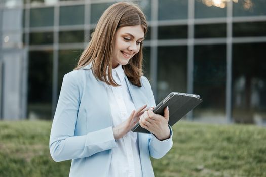 Beautiful young woman engaged in business using tablet computer reading financial news online. European hairstyle. Corporate people.