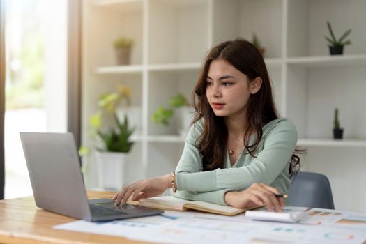 Young accountant freelance working in office using laptop with calculator. concept business finance and accounting, tax, debt concept.