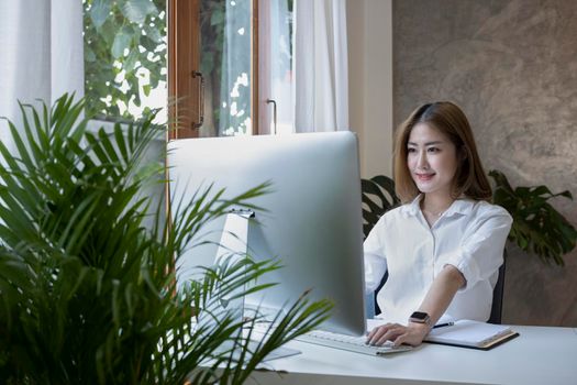 Happy young woman entrepreneur working with computer at comfortable workplace.