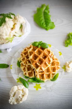 vegetable waffles cooked with cauliflower in a plate on a wooden table.