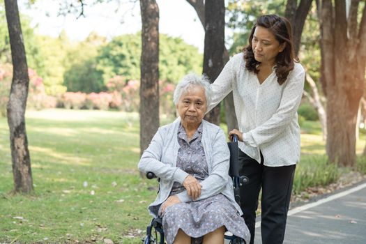 Caregiver help and care Asian senior or elderly old lady woman patient sitting and happy on wheelchair in park, healthy strong medical concept.