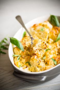 baked cauliflower with vegetables and cheese and scrambled eggs in a ceramic dish