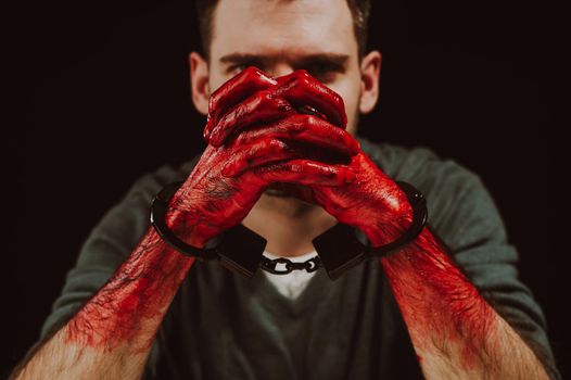 Portrait of a man with bloody hands handcuffed