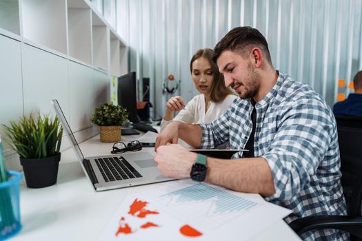 Two entrepreneurs man and woman sitting together working in an office, close up