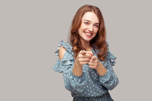 Hey you. Lovely happy brunette girl ruffle dress pointing finger looking at camera, noticing lucky winner, indicating choosing and smiling friendly. indoor studio shot isolated on gray background