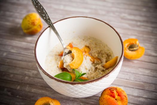 Healthy breakfast of boiled oatmeal with fresh apricots in a bowl on the table.