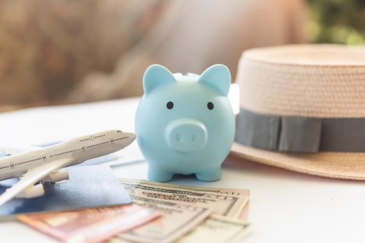 Save money for airplane tickets, planning travel budget concept. Airplane model, piggy bank on wooden table.