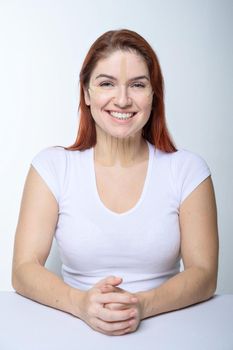 Portrait of a redhead woman with tapes on skin color face for rejuvenation. An alternative way to fight wrinkles