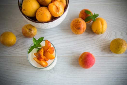 Healthy breakfast of homemade yogurt in a glass with fresh apricots on the table.