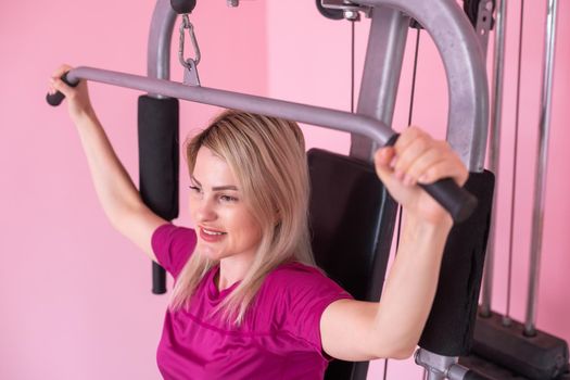 woman wearing pink and black professional sportswear pulling up at the gym. Strength and motivation concept