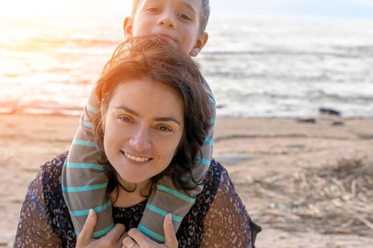 Cute happy preschooler boy hugs his mom on the seashore in the sunset light. love for parents. Close family relationships