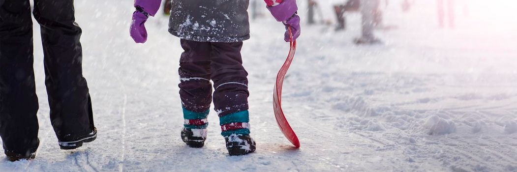 The girl is holding a red sled in her hands to ride the hill. Sledging. Activities for children and teenagers. Winter entertainment and sports