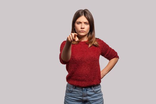 Hey you. Portrait of angry bossy brunette woman in shaggy sweater pointing finger to camera, looking with suspicion and accusing, choosing guilty. indoor studio shot isolated on gray background