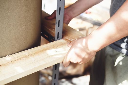 A carpenter measures the planks to assemble the parts, and build a wooden table for the customer