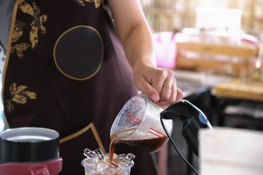 A female employee pours coffee into a plastic cup for customers.