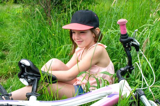 a child girl has damaged a bicycle wheel and is making repairs photo without processing. High quality photo