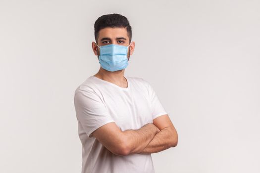 Effective protection against coronavirus. Man holding hands crossed and wearing hygienic mask to prevent infection, respiratory illness such as flu, 2019-nCoV. indoor studio shot, white background